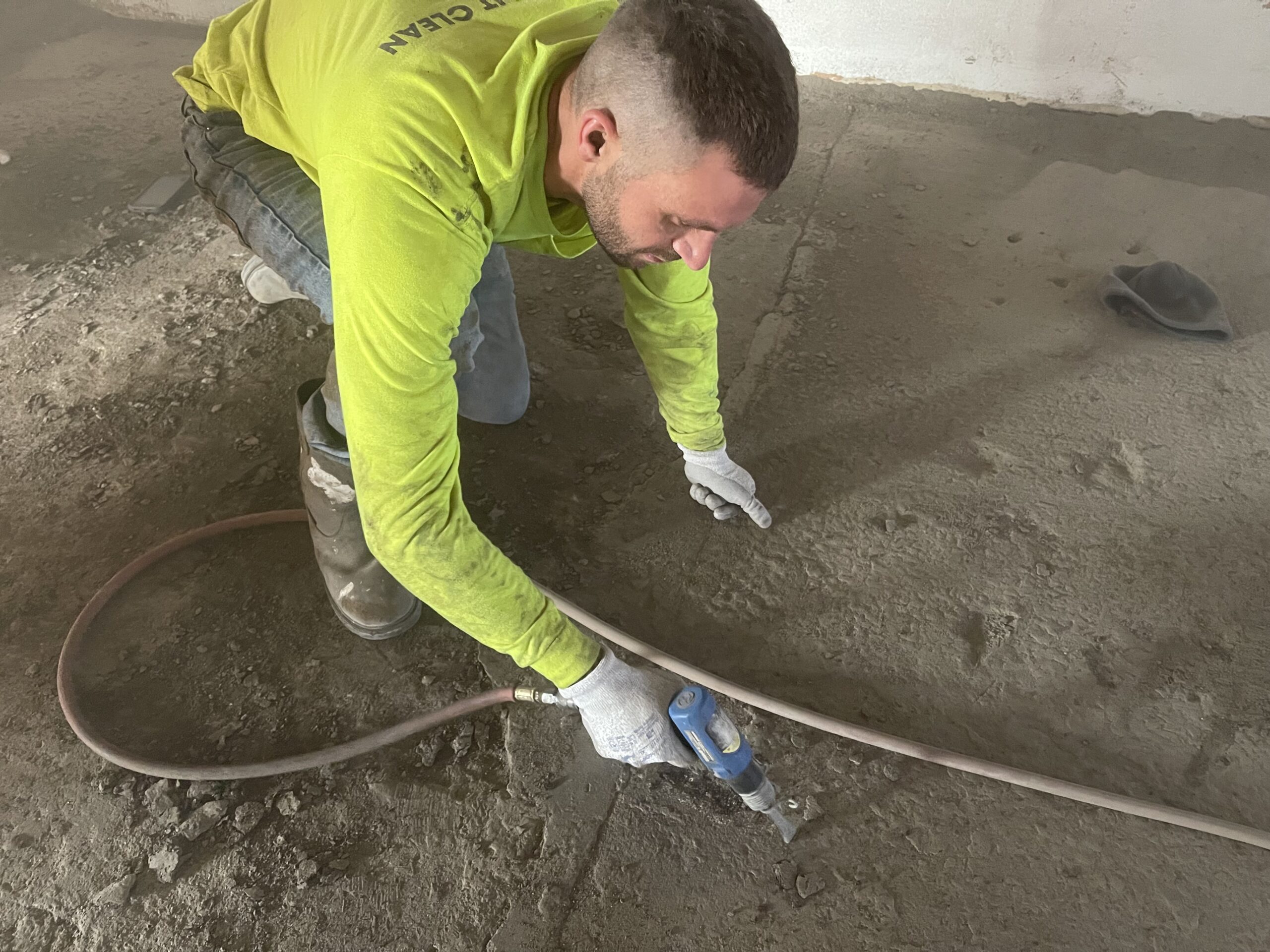 payton crew member drilling oil chunks off of concrete floor