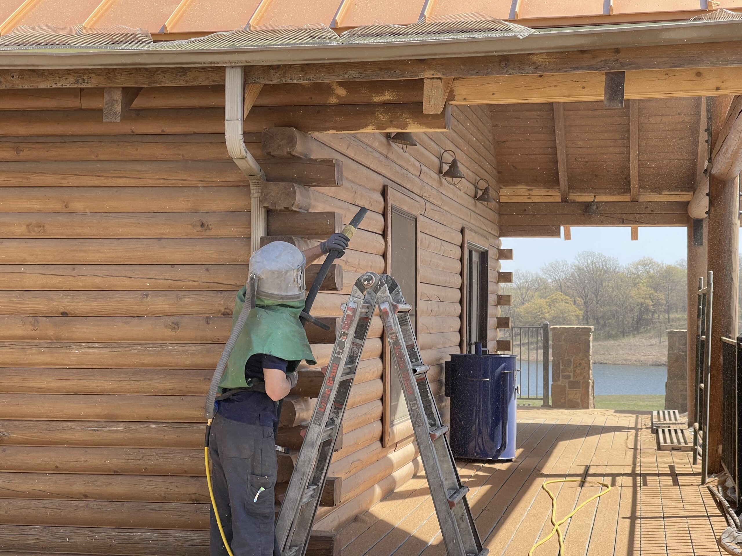 crew member in process of sandblasting side of wood paneled house crew member in process of sandblasting side of wood paneled house