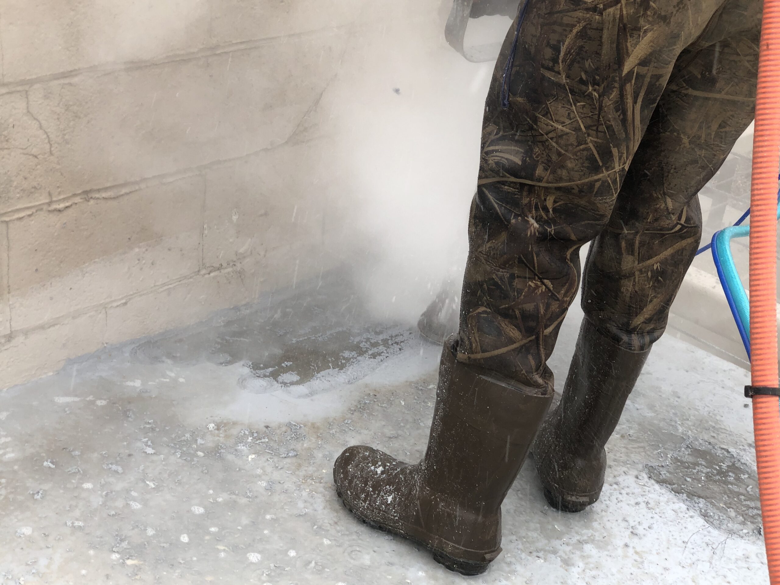 man's legs in view while sandblasting concrete ground