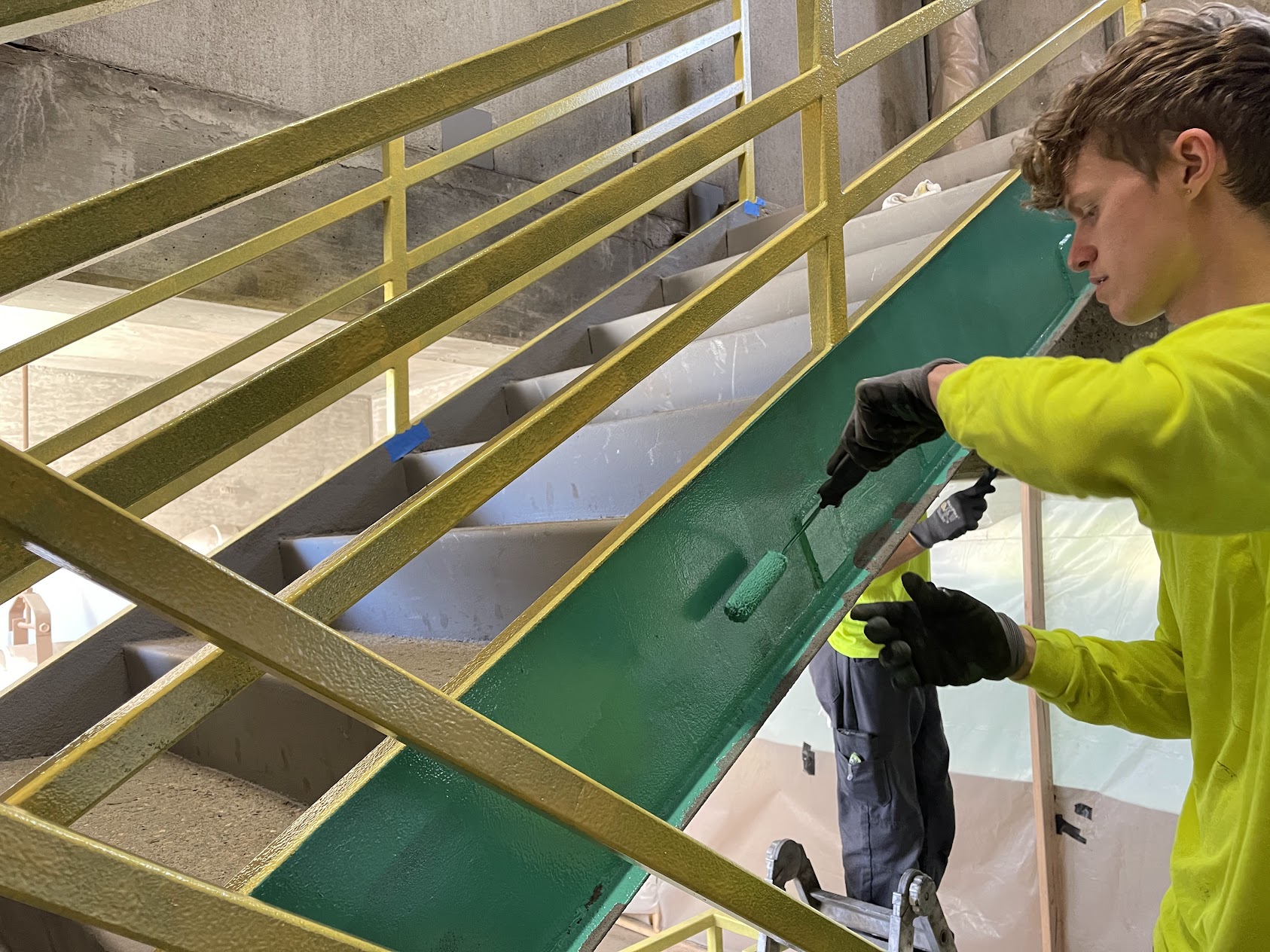 Man in high visibility shirt painting side of staircase Man in high visibility shirt painting side of staircase