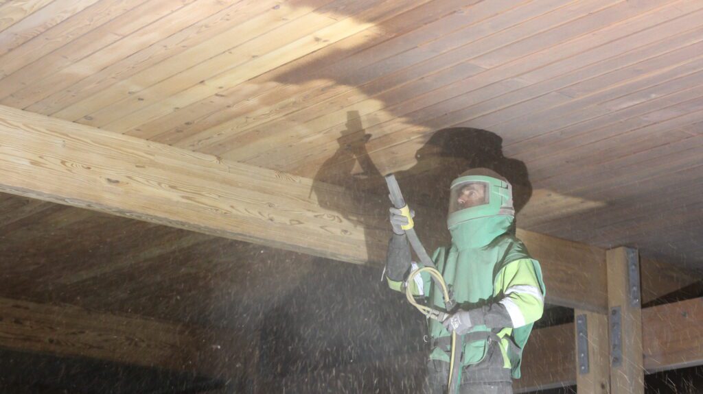 crew member using special media for sandblasting wood ceiling