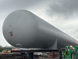 large storage tank with construction equipment in background
