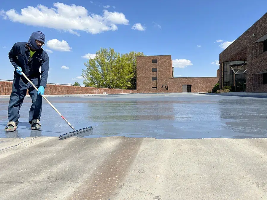 construction worker laying a protective coating on concrete parking lot