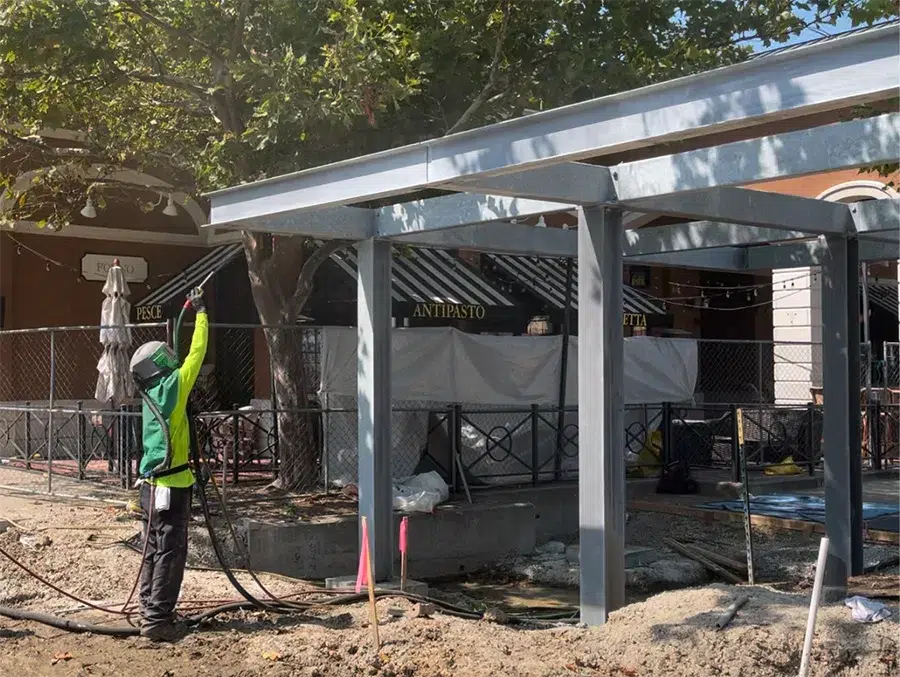 construction worker sandblasting newly constructed steel beams prepped for protective coating