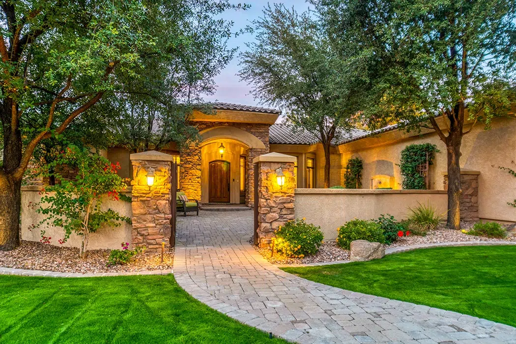 Luxury home sunset with brick walkway and green grass and trees Luxury home sunset with brick walkway and green grass and trees