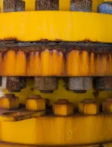 Corrosion and rust staining around the bolts and joint of a yellow industrial pipe flange.