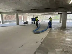 Crew uses a shot blasting machine to remove a coating from a concrete floor.