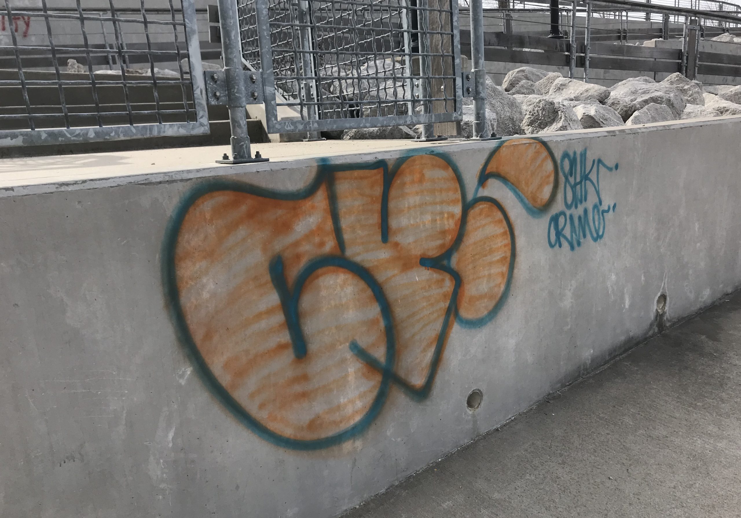 orange and blue graffiti on concrete wall